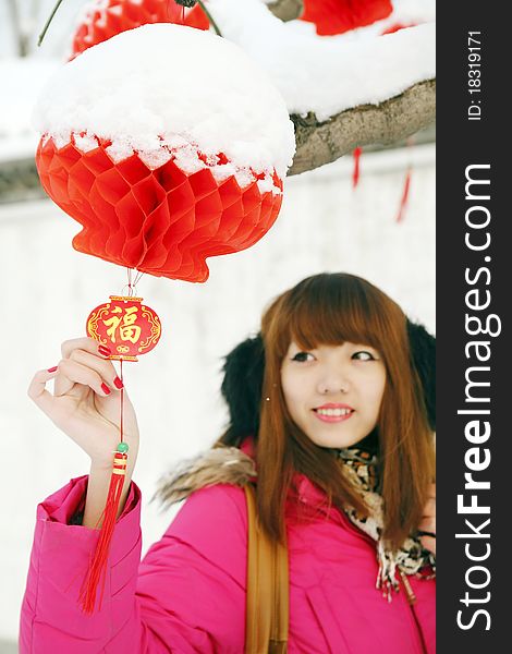 After New Year's first snow,it symbolizes good luck. Beautiful Chinese girl enjoying red lantern and Chinese knot in Chinese new year.(Focus on the lantern and knot) Chinese characters on Chinese knot are Good Fortune .