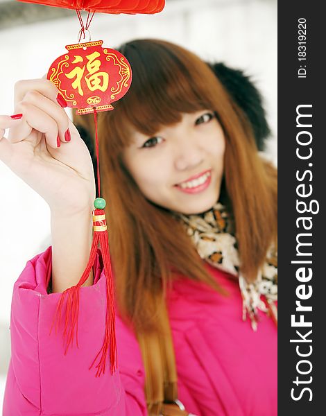 After New Year's first snow,it symbolizes good luck. Beautiful Chinese girl holding the Chinese knot in Chinese new year.(Focus on the Chinese knot) Chinese characters on Chinese knot are Good Fortune .