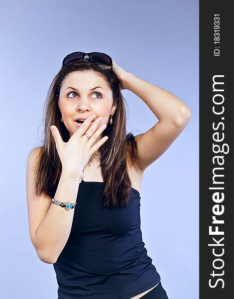 A girl delighted and astonished, covers her mouth with one hand and holding his head with his other hand