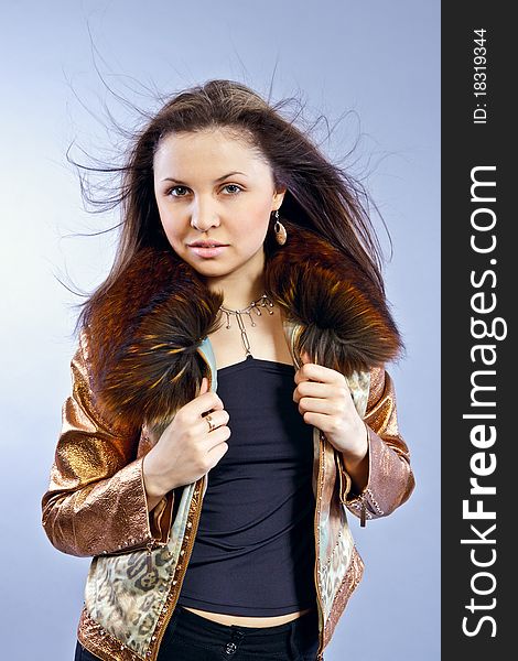 Beautiful fashion girl, dressed in light-brown jacket with collar, with flowing hair the in the wind