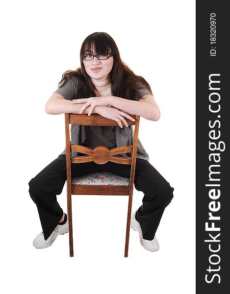 A young girl sitting backwards on an old chair, with glasses, for white background.