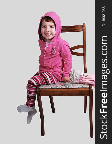 A nice little girl in a coat sitting on a chair and smiling into the camera, on whit background. A nice little girl in a coat sitting on a chair and smiling into the camera, on whit background.