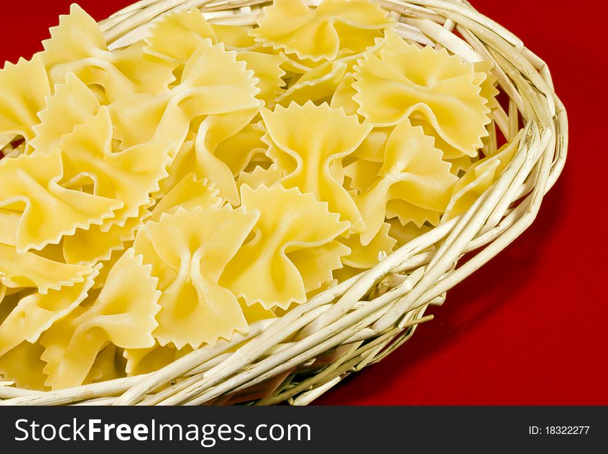 A close up of s wicker basket filled with uncooked farfalloni pasta. A close up of s wicker basket filled with uncooked farfalloni pasta
