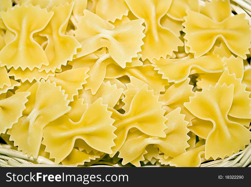 A close up of a wicker basket filled with uncooked farfalloni pasta. A close up of a wicker basket filled with uncooked farfalloni pasta