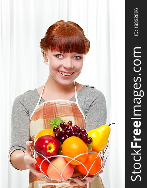 Ginger housewife holding fruits over white