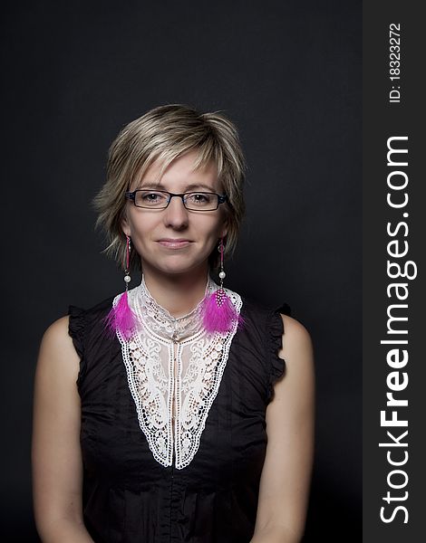 Portrait of attractive woman with pink feather earrings on black background. Portrait of attractive woman with pink feather earrings on black background