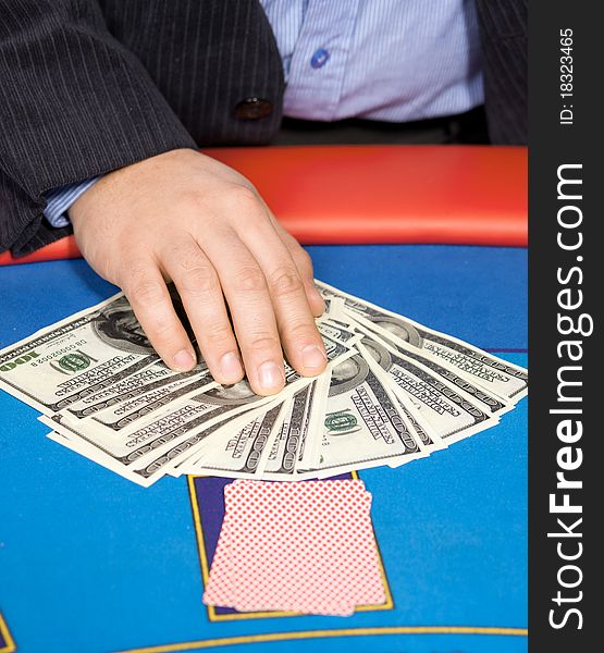 Close up of men's hand with cards and one hundred dollars banknotes on poker table. Close up of men's hand with cards and one hundred dollars banknotes on poker table