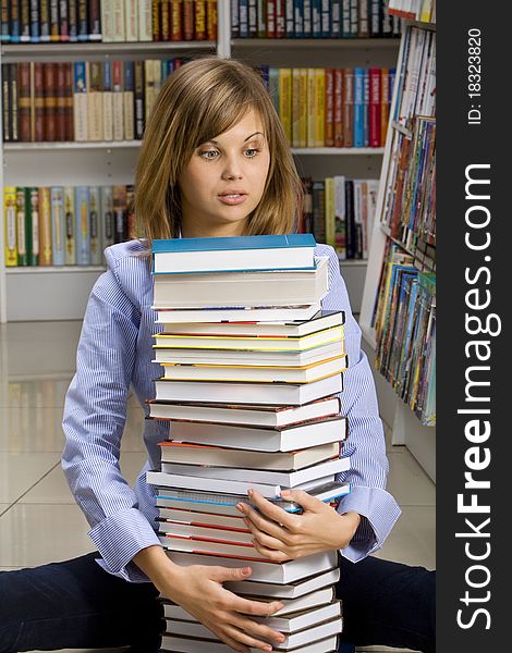 Young woman sitting with stack of books in the library. Young woman sitting with stack of books in the library