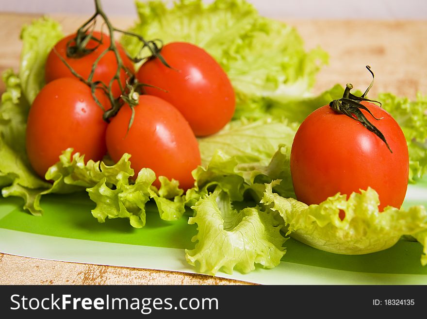 Branch of tomatos. Group red tomatos on leaf lettuce.