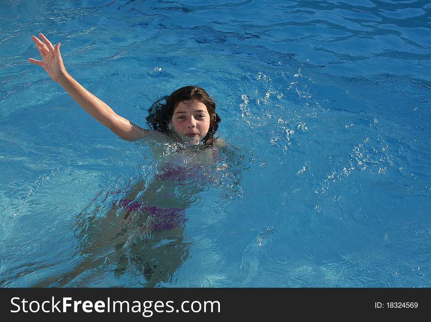 Girl swimming and waving to the camera.
