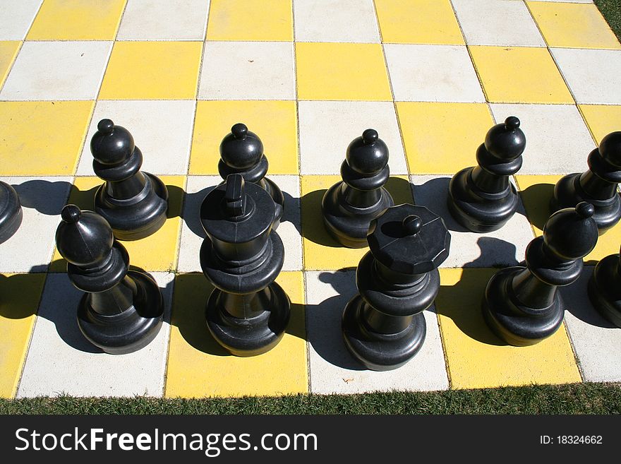 Close up of black chess pieces on a large board.