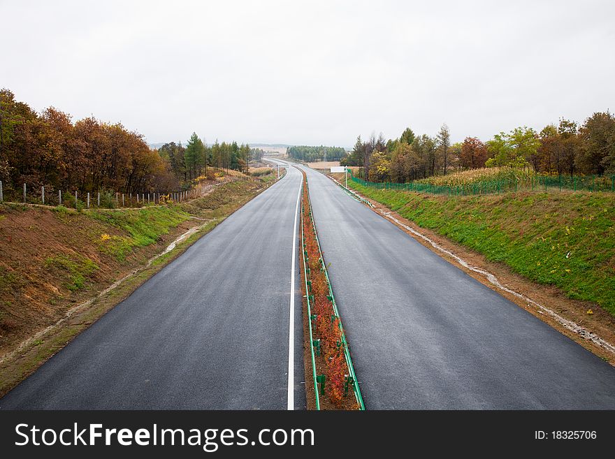 Highway through bushes and woods.