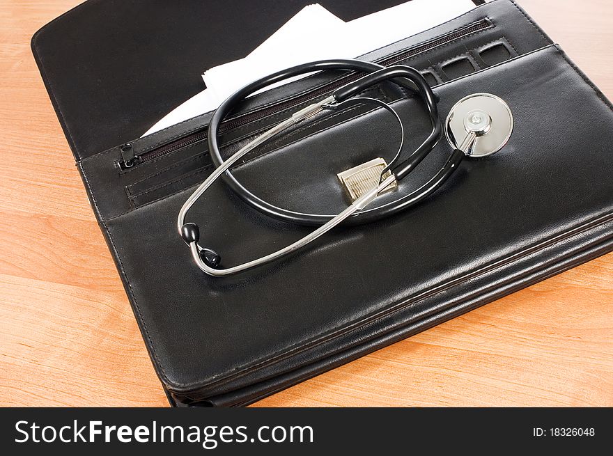 Black portfolio and phonendoscope on a table still life