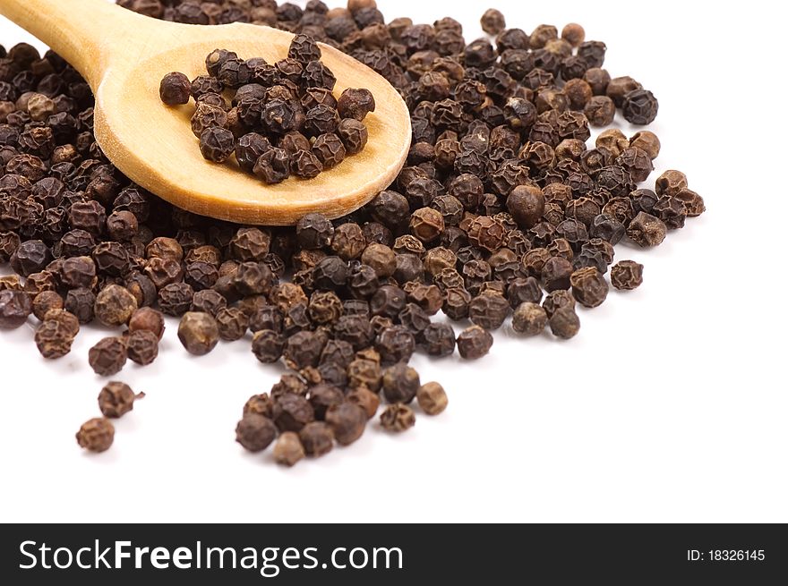 Black Peppercorns on a wooden spoon on white