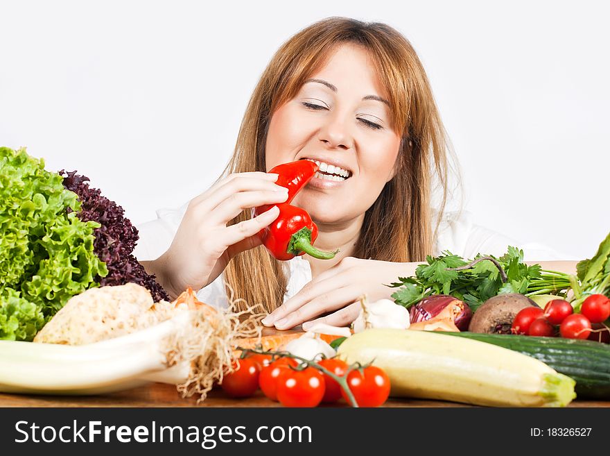 Young woman eating red pepper with mixed vegetable on table. Young woman eating red pepper with mixed vegetable on table.