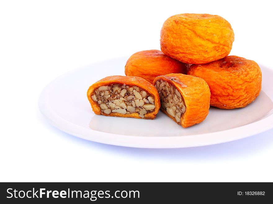 Dried peaches stuffed with nuts in plate isolated on white background.