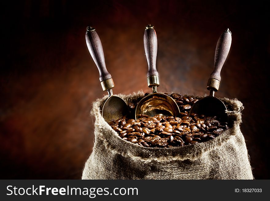 Sack of coffee beans and scoop. On a dark background.