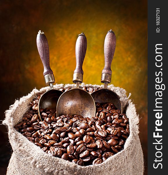 Sack of coffee beans and scoop. On a dark background.