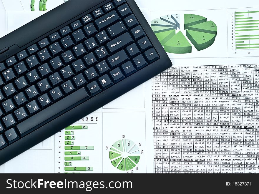 Black keyboard on a stock green chart and numbers. Studio shot. Black keyboard on a stock green chart and numbers. Studio shot