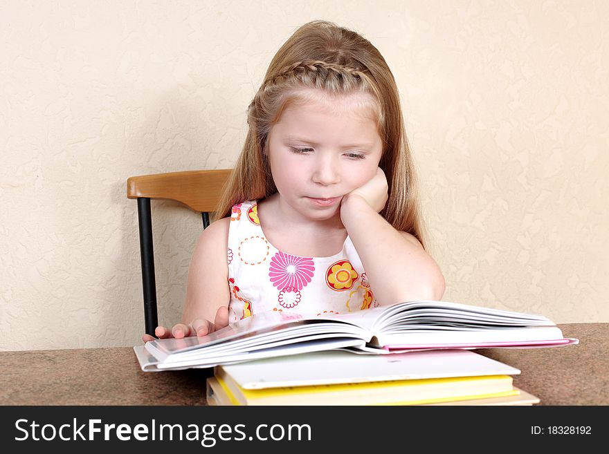 Little girl reading book against yellow wall at home