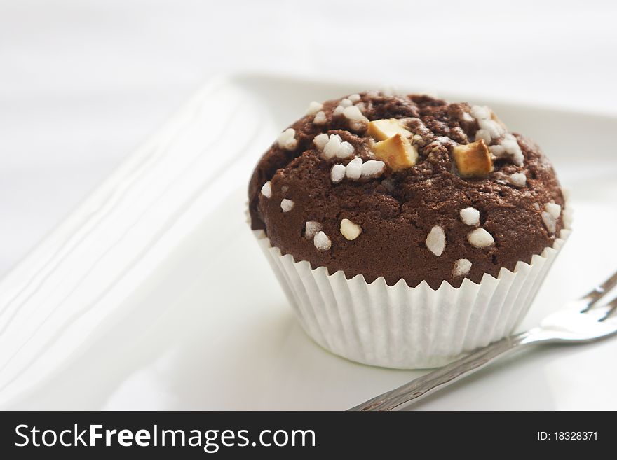 Chocolate muffin sprinkled with white chocolate pieces and decoration. Chocolate muffin sprinkled with white chocolate pieces and decoration