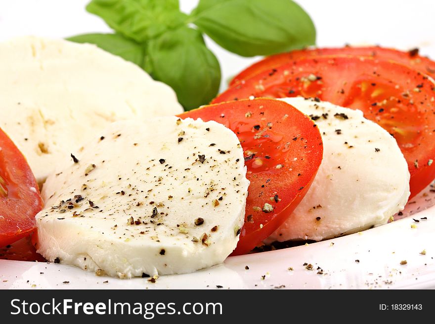 Mozzarella and tomato slices with pepper and basilicas. Mozzarella and tomato slices with pepper and basilicas.