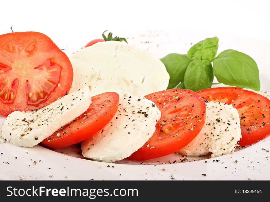 Mozzarella and tomato slices with pepper and basilicas. Mozzarella and tomato slices with pepper and basilicas.