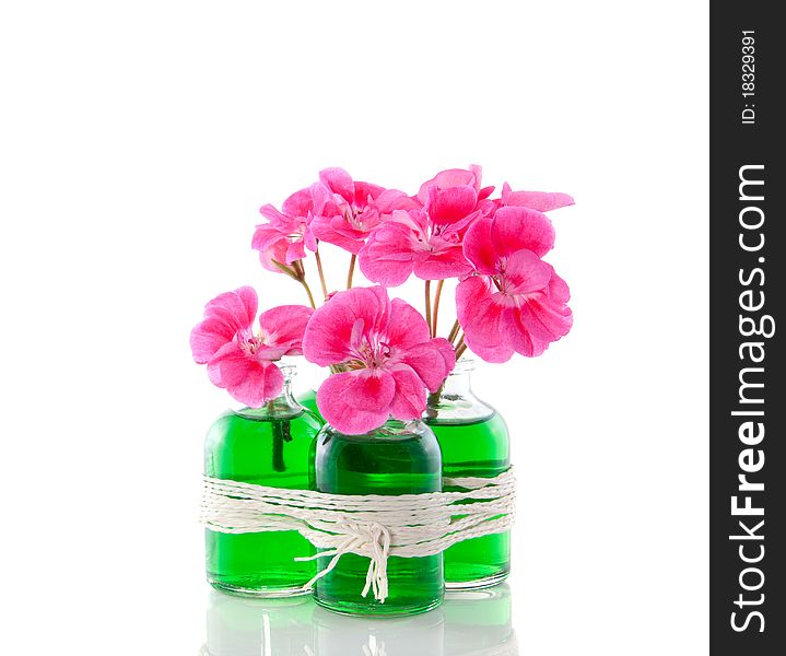 Pink geranium in four little glass vases with green liquid isolated over white. Pink geranium in four little glass vases with green liquid isolated over white