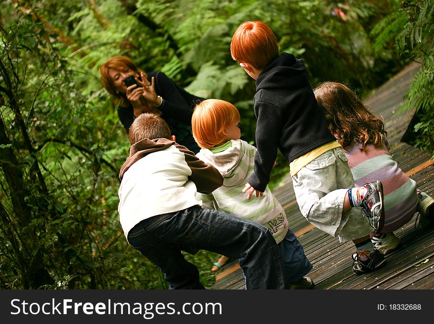 Red haired woman photographing a group of children in a forest. Red haired woman photographing a group of children in a forest