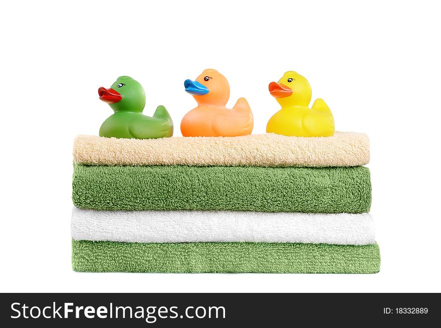Green and white towels with rubber ducks toys on them isolated on white