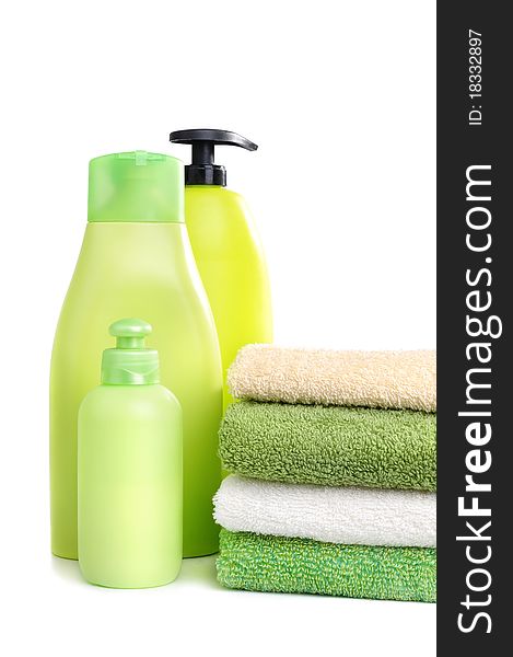 Green and white towels and green plastic bottles of shampoo isolated on white