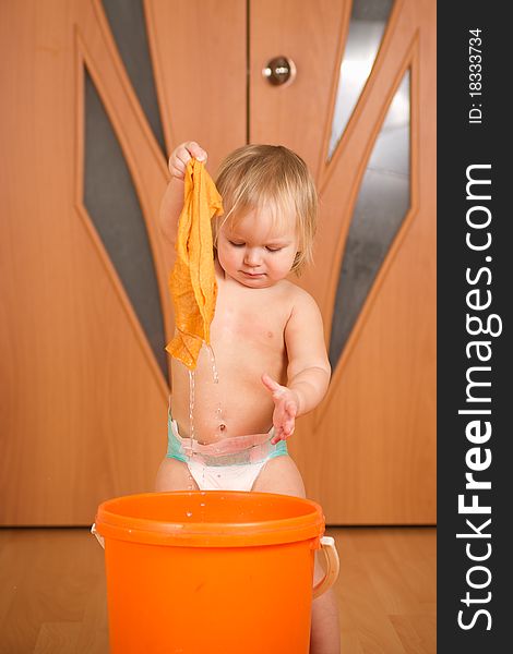 Adorable baby holding wet rug after washing it