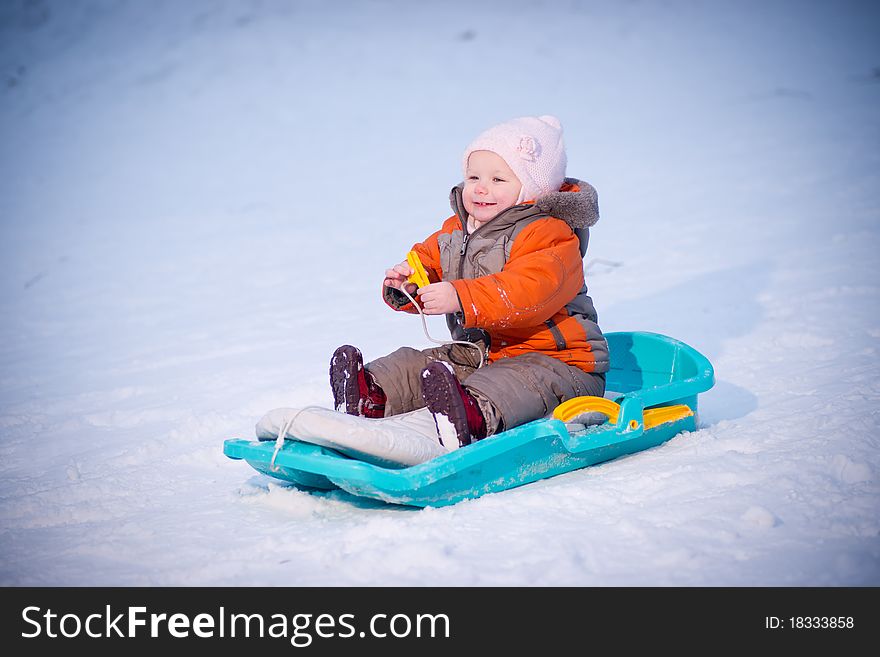 Adorable baby sliding on sleigh from hill