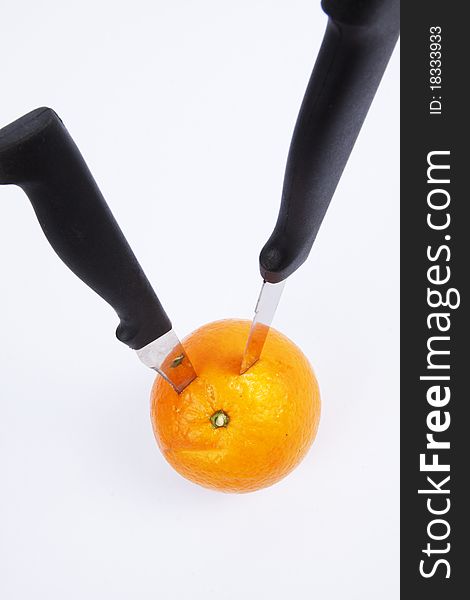 Two black knife stab on an orange. Two black knife stab on an orange.