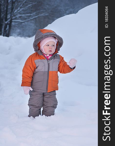 Cute baby walk in deep snow in winter evening park playground