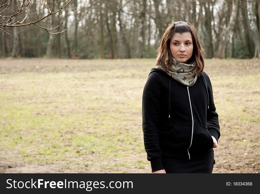 Young woman standing on the grass. She wears a black sweater