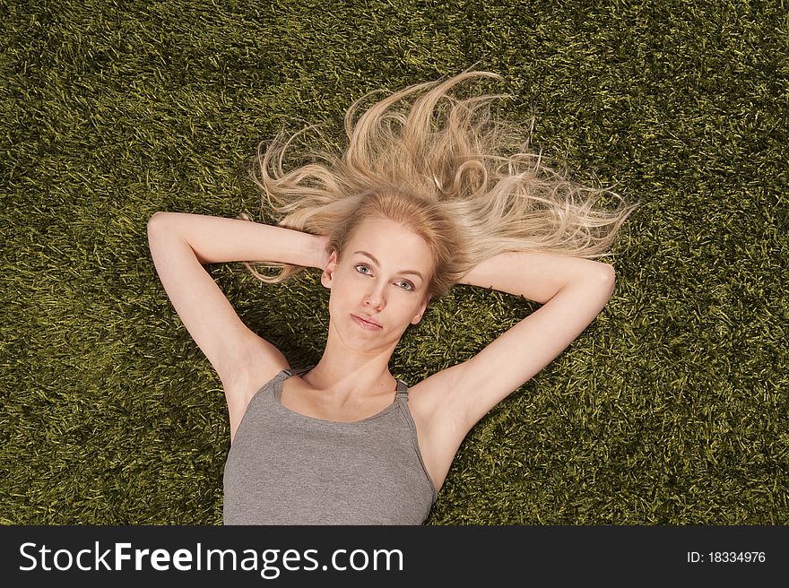 Blond young woman is lying on the grass carpet. Blond young woman is lying on the grass carpet.