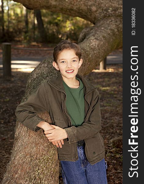 Outdoor portrait of young boy and large oak tree