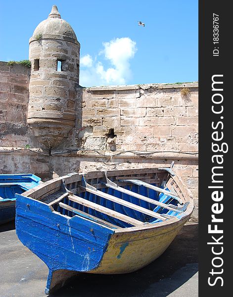 A colorful boat sits next to a medieval wall while waiting to go out to sea. A colorful boat sits next to a medieval wall while waiting to go out to sea.