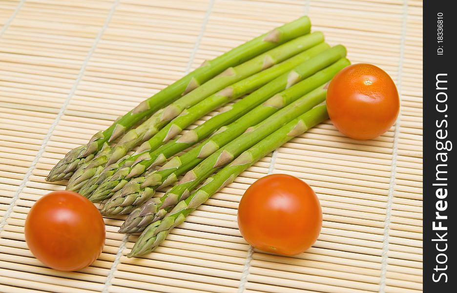 Asparagus stems and tamatos on bamboo substrate