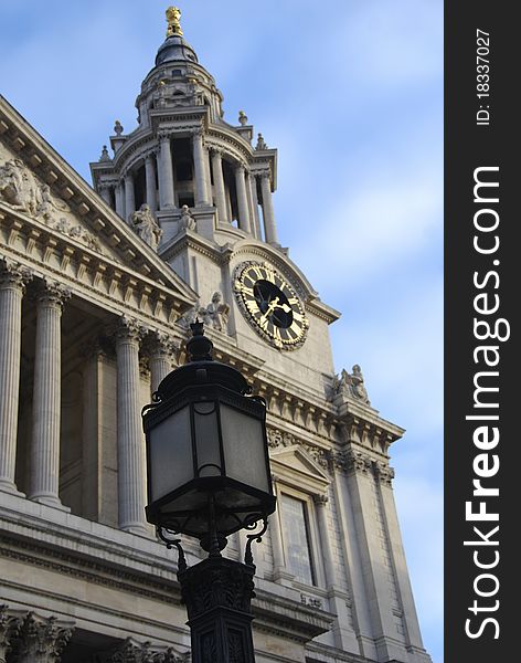 St. Paul's Cathedral Clock Tower glistens in the sunlight with a streetl lamp standing in front. St. Paul's Cathedral Clock Tower glistens in the sunlight with a streetl lamp standing in front