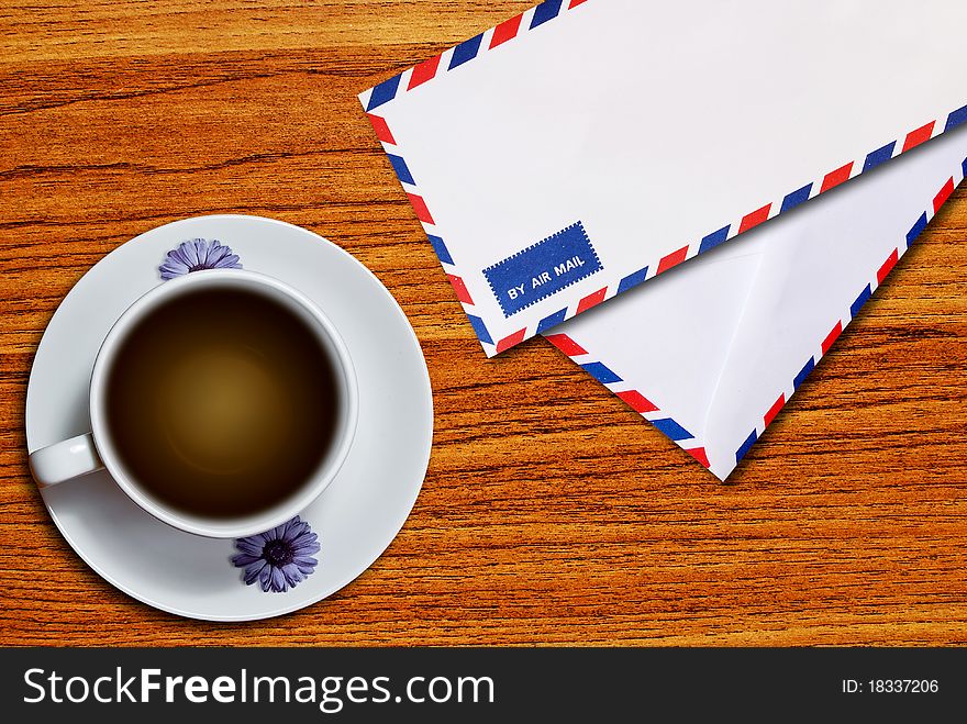 Air mail envelope and coffee cup on wood table background