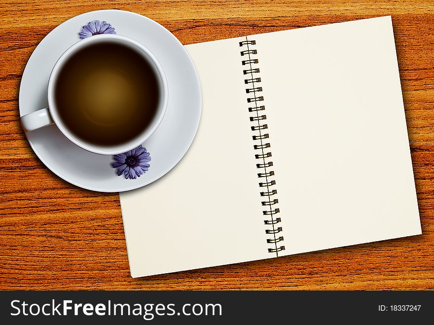 White cup of coffee and blank page notebook on wood table background. White cup of coffee and blank page notebook on wood table background