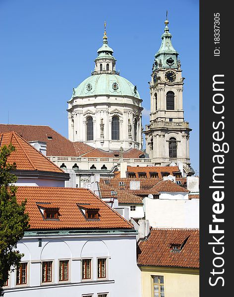 Steeple and dome of the cathedral of St. Nicholas peaking over the Prague red roofed skyline. Steeple and dome of the cathedral of St. Nicholas peaking over the Prague red roofed skyline.