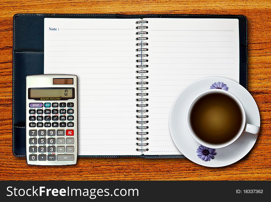 White cup of coffee and calculator on blank page notebook on wood table background