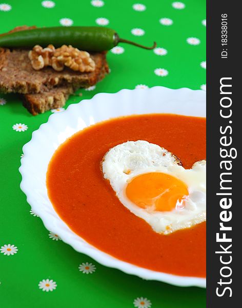 Tomato soup with egg on a green background