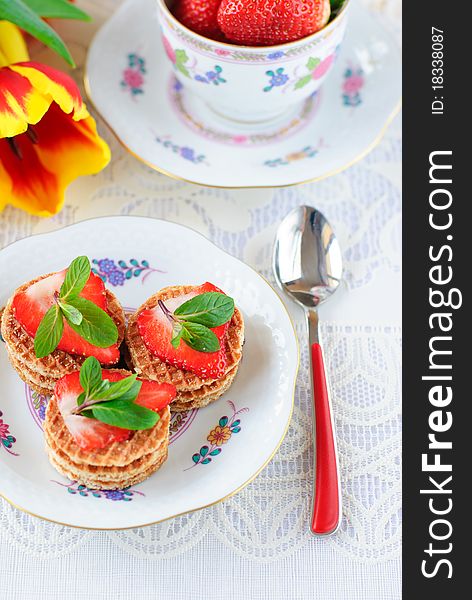 Cakes with fresh strawberry and mint, cup with strawberries and tulips flowers
