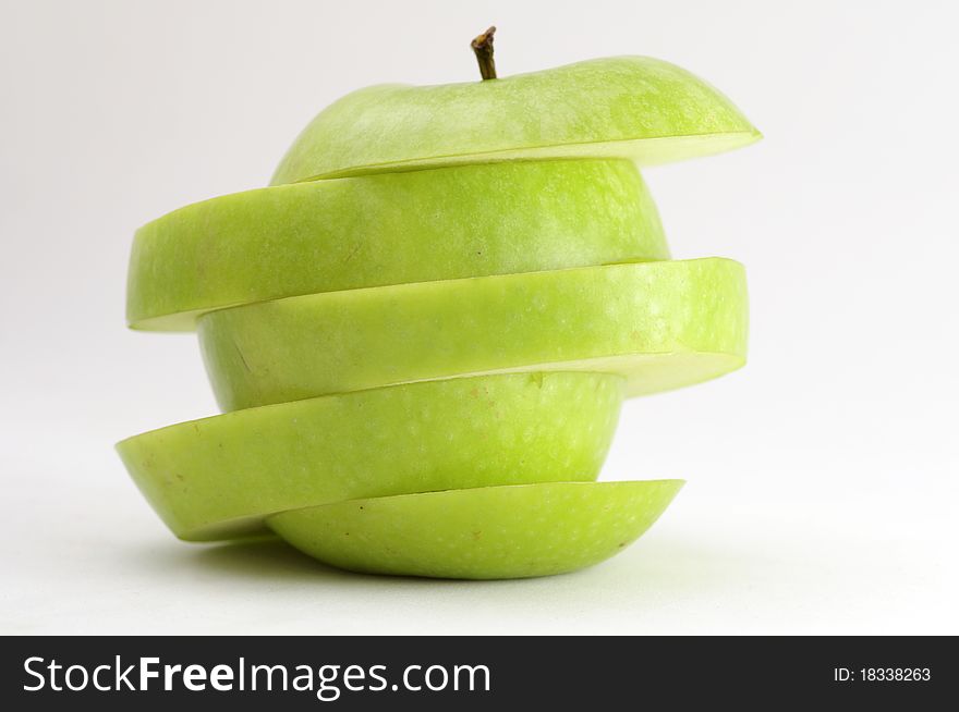 A green apple sliced diagonally. Isolated on neutral background. A green apple sliced diagonally. Isolated on neutral background.