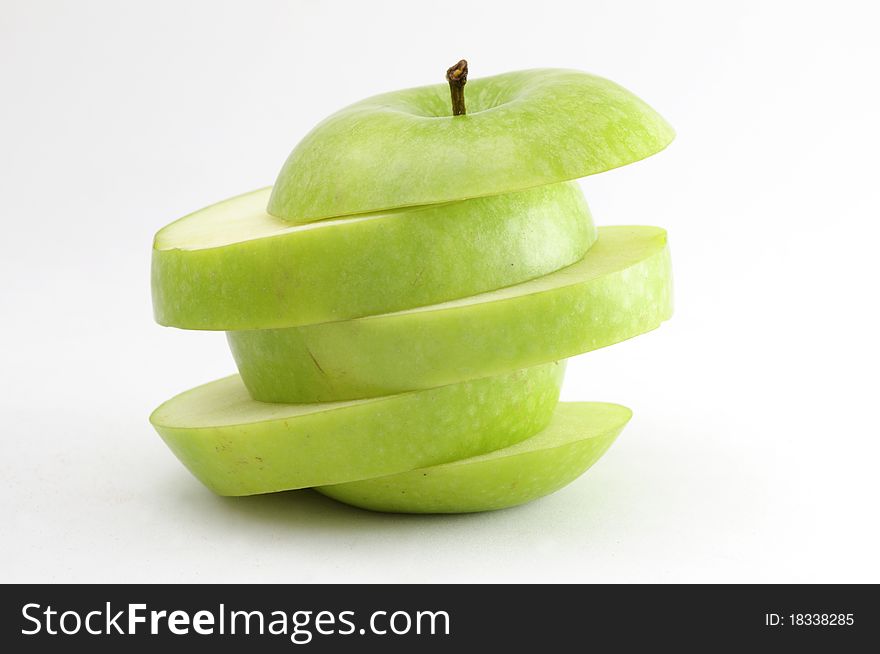 A green apple sliced diagonally. Isolated on neutral background. A green apple sliced diagonally. Isolated on neutral background.