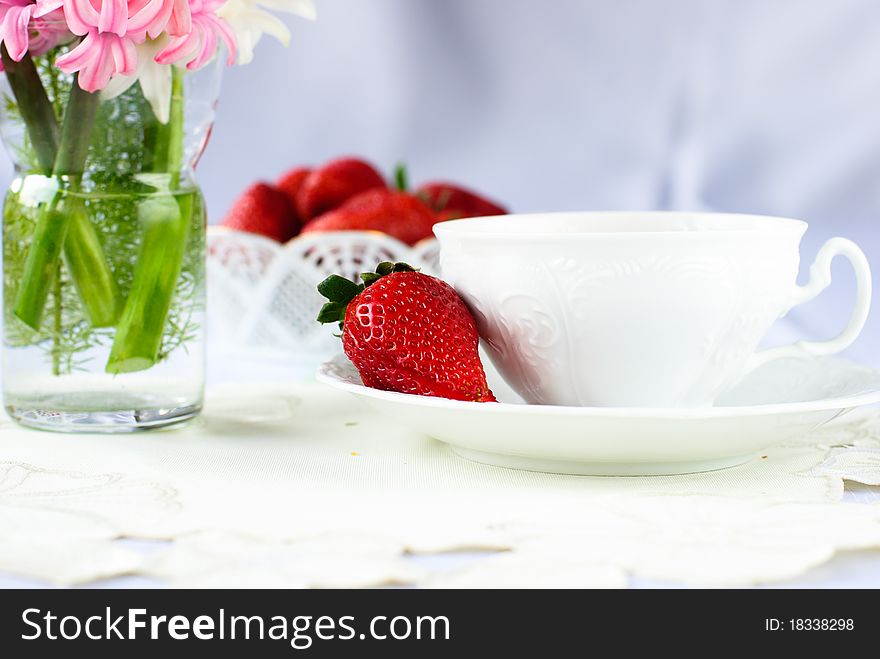 Cup saucer and strawberry and hyacinth flowers on white napkin. Cup saucer and strawberry and hyacinth flowers on white napkin